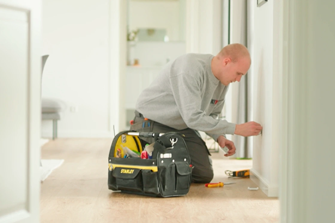 En elektriker fra Uggerly Installation som står foran en kundes hus og hans servicevogn.