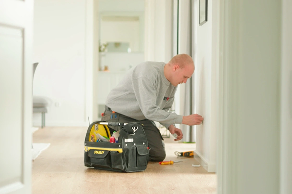 En elektriker fra Uggerly Installation som står foran en kundes hus og hans servicevogn.